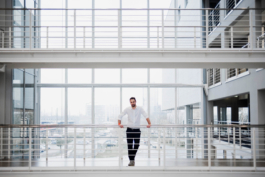 Businessportrait einer Führungsperson in riesiger Empfangshalle mit Blick durch Fensterfront auf Skyline