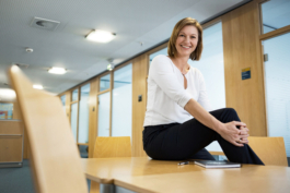 Geschäftsführerportrait der Dortmunder Stadtplanerin Frau Linnebach. Lässig sitzend in moderner Büroumgebung mit Stuhl im unscharfen Vordergrund.