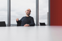 Portrait des Intendanten des Dortmunder U Edwin Jacobs. Sitzend im Archiv und lachend zu einem nicht sichtbaren Gesprächspartner.