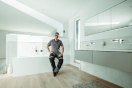 Mitarbeiterportrait eines Handwerkers für ein Testimonial. Sitzend in sonnendurchflutetem, hochwertigen Badezimmer.