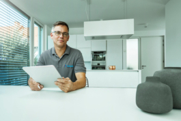 Portrait eines Handwerkers bei einer Beratungssituation in hochmoderner Küche mit Tablet in der Hand.