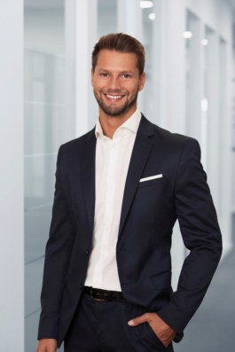 Businessportrait eines Angestellten im Bereich Human Resources vor hellem Bürohintergrund.