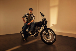 Werbefotografie eines restaurierten Motorrads mit seinem neuen Besitzer. Das Motorrad steht in einer Vintage Umgebung im morgendlichen Sonnenlicht. Der Käufer sitzt stolz seitlich auf dem Rücksitz.