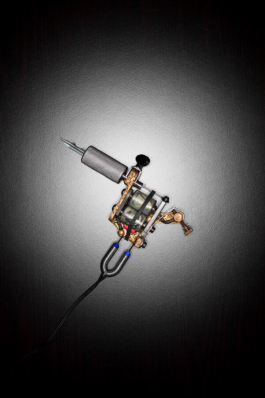 Werbeaufnahme einer edlen Tätowiermaschine auf schwarzem Hintergrund.