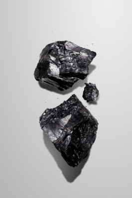 Imageaufnahme von Kohlestücken auf neutralem, hellgrauen Hintergrund.