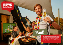 Werbefotografie für die Firma REWE. Im Vordergrund hält einer junger Mann ein Sektglas in die Höhe um den Betrachter zu Grüßen. Er grillt gleichzeitig Würstchen der REWE Hausmarke. Im Hintergrund sitzen seine Freunde und schauen ein WM Spiel der deutschen Nationalmannschaft. Alle tragen Trikots und Fanartikel des DFB